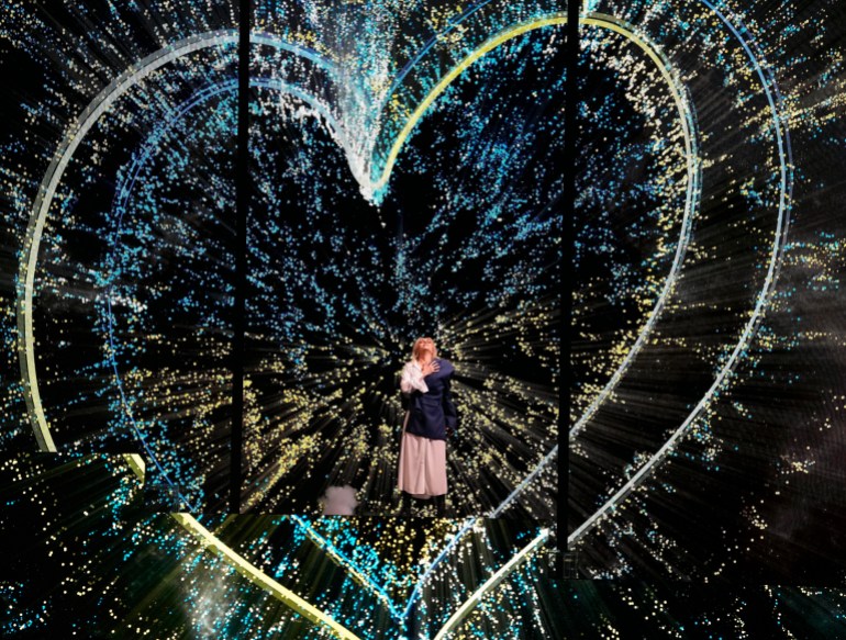 Ukrainian singer Alyosha performs in front of two handdrawn hearts in the blue and yellow of Ukraine