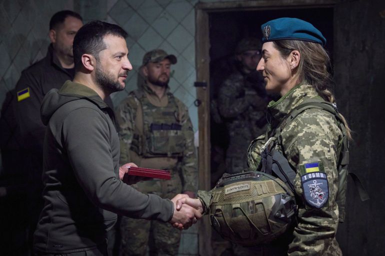 Ukrainian President Volodymyr Zelenskyy shakes hands with a servicewoman during an awarding ceremony as he visits the Donetsk region, Ukraine, Tuesday, May 23, 2023.