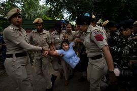 Olympic bronze medallist Sakshi Malik, in blue, is detained by police during a protest near the Indian Parliament in New Delhi on May 28, 2023 [Altaf Qadri/AP]