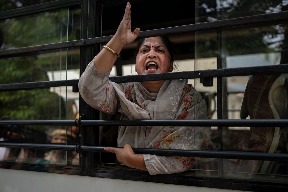 An activist who had come to support protesting wrestlers shouts slogans as she is detained by the police