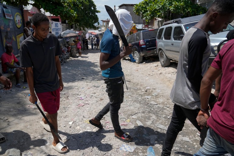 Members of the 'Bwa Kale' vigilante movement walk in a street with machetes