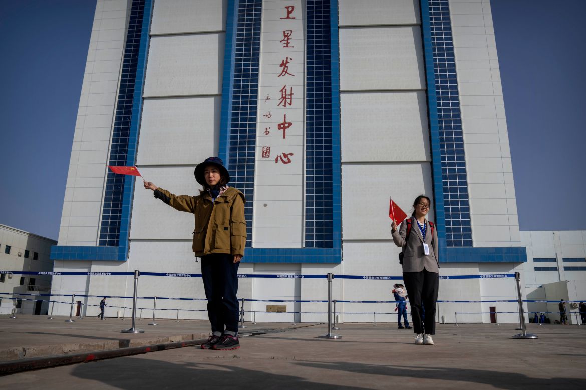 Visitors waving Chinese flags pose for photos before the liftoff of the Shenzhou-16 spaceship