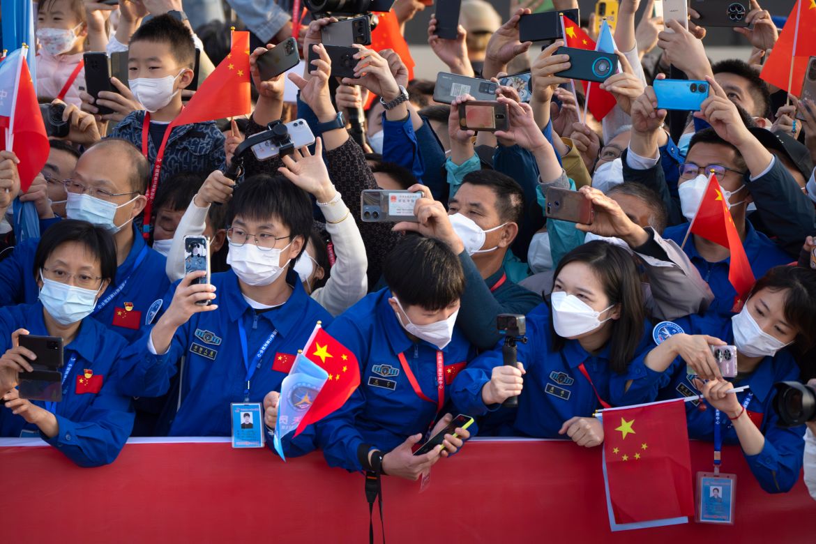 Staff members take photos as Chinese astronauts arrive for a send-off ceremony