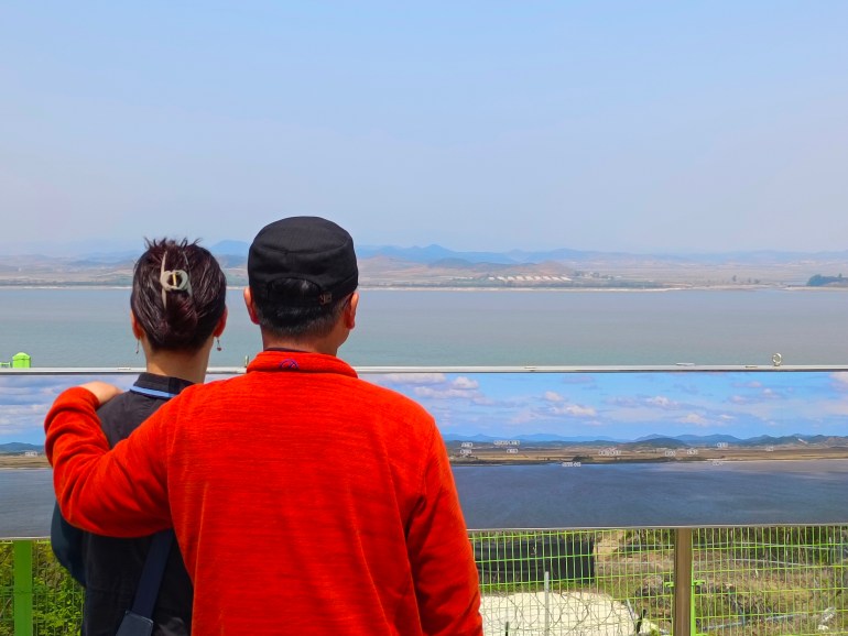 Couple looking at North Korea across the Han River estuary at the Ganghwa Peace Observatory. It's a sunny day with a cloudless sky