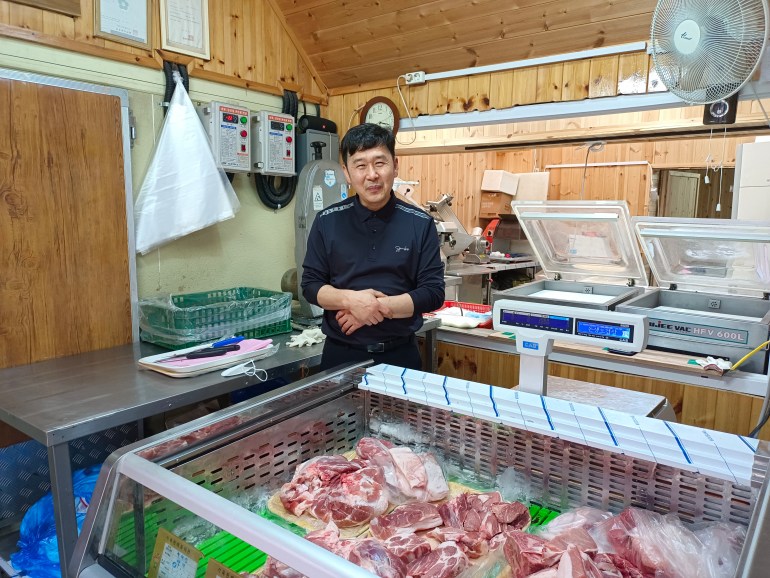 Choi Seong-ho smiling next to his meat fridge at the Daeryong Market at the North Korean border. 