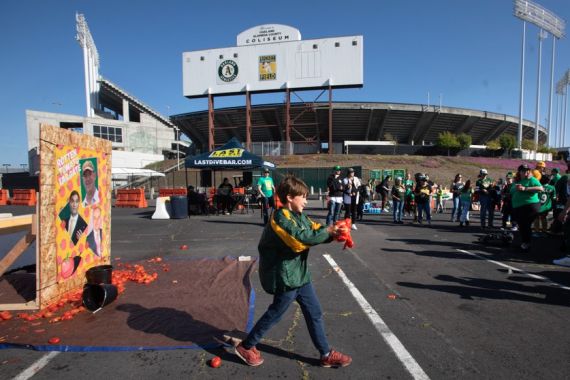 Oakland A fans throw tomatoes at a picture of owner John Fisher