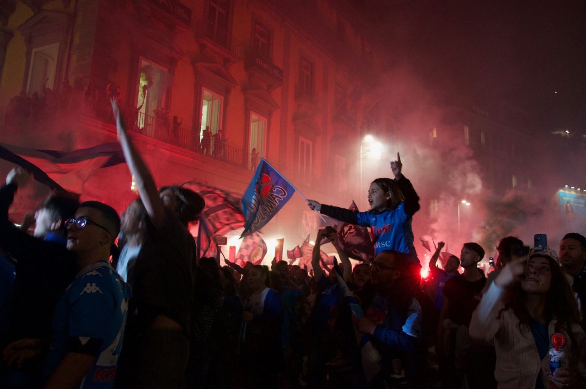 A child sits on their parent’s shoulders shouting and waving around a Napoli fan after the team secured their title as the 2023 Italian champions; a title that has not been won by the team since 1990. [Savin Mattozzi/Al Jazeera]
