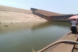 In videos that went viral on social media, Vishwas is seen sitting under a red umbrella as diesel pumps run to drain water from the reservoir [Still from social media video]