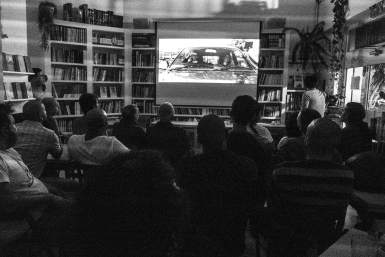 Black and white photo of a group of people gathered in front of a screen for a movie