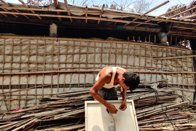 Nur Ayesha’s husband fixing the solar panel in front of their damaged shelter