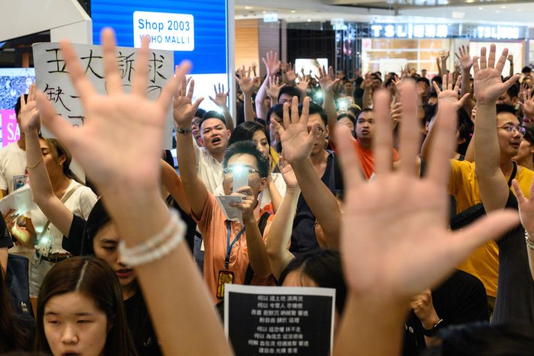 People hold up their hands as they sing 'Glory to Hong Kong' in a shopping mall in 2019