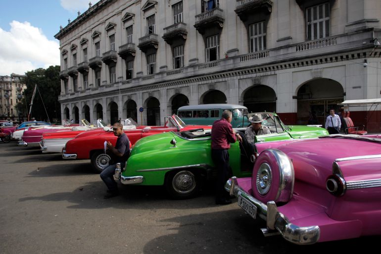 Drivers stand near their vintage cars waiting for clients in Havana December 17, 2014. Stunned Cubans celebrated an apparent end to decades of conflict with the United States on Wednesday after both governments said they would restore diplomatic relations cut off in 1961. Many said they expected a restoration of ties would lead to the end of a U.S. economic embargo against Cuba, which is vilified daily in the official media and which Cubans accept as a key cause of widespread poverty on the island. REUTERS/Stringer (CUBA - Tags: POLITICS TRANSPORT SOCIETY BUSINESS EMPLOYMENT)