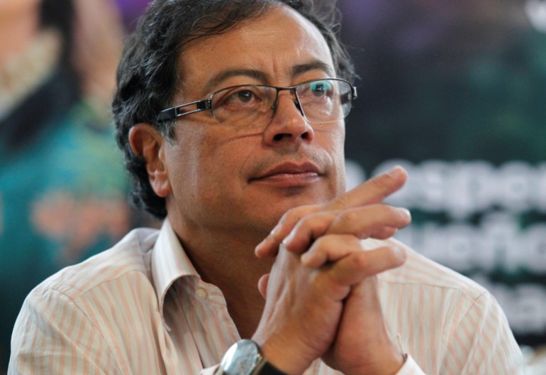 Colombian presidential candidate Gustavo Petro meets with supporters ahead of Sunday's presidential race. He is seen in a white collared shirt, with his hands folded near his face.