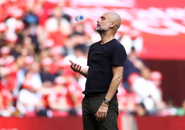 Guardiola throws a water bottle into the air