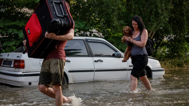 Residents carry their belongings in a flooded street after the Nova Kakhovka dam breached, Kherson, Ukraine