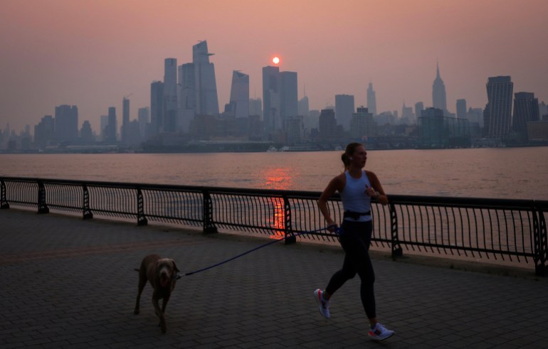 A woman jogs along the Hudson River as haze and smoke caused by wildfires in Canada fill the air behind her