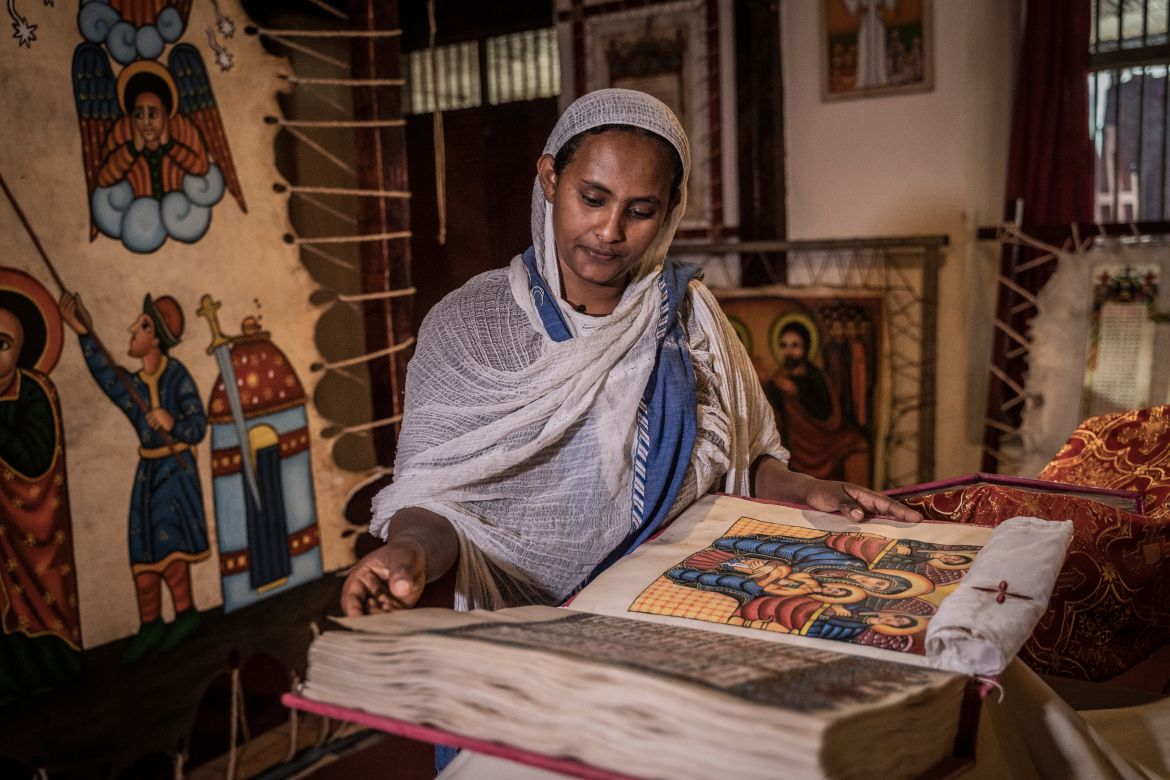 Yeshiemebet Sisay , 29, a member of the Hamere Berhan initiative and public relations officer looks at a Ge'ez language scriptural book written on goat skin parchment in Addis Ababa