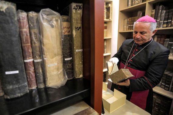 In this picture taken on May 16, 2023, the Chaldean Catholic Archbishop of Mosul Michaeel Najeeb retrieves an old Christian book at the Eastern Manuscript Digitisation Centre (CNMO) in Arbil