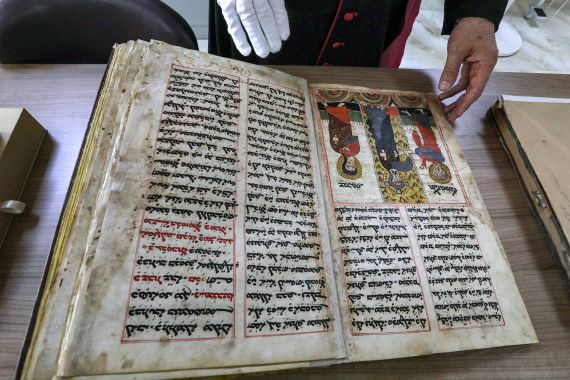 In this picture taken on May 16, 2023, the Chaldean Catholic Archbishop of Mosul Michaeel Najeeb presents an old Syriac-language Christian codex