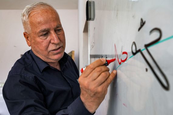 Syriac language teacher Salah Sarkis writes on a whiteboard as he gives a class at the Ashurbanipal Syriac School in Iraq's predominantly Christian town of Qaraqosh (Baghdeda)