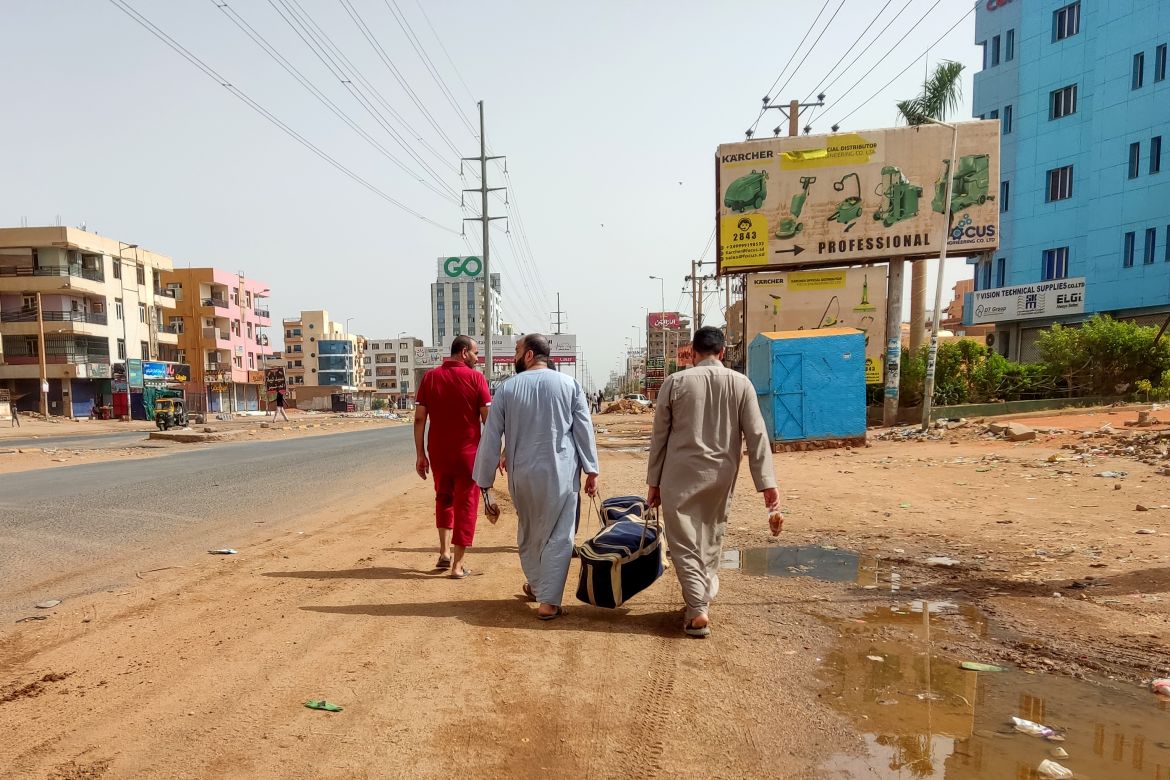 Sudanese people walk with their luggage in Khartoum
