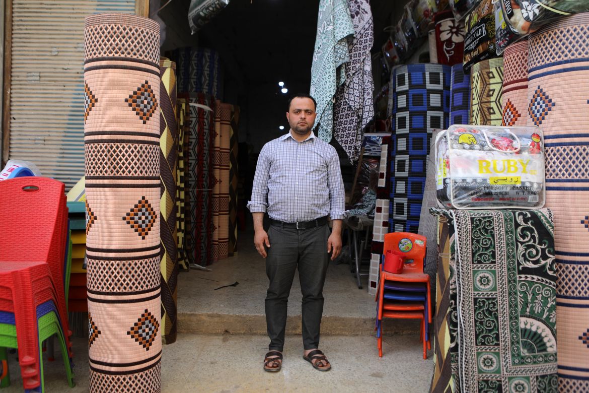 a merchant displays mats and rugs made from recycled plastic
