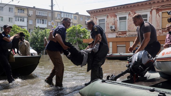 Ukrainian security forces carry an elderly resident to a boat during an evacuation from a flooded area in Kherson on June 7, 2023, following damages sustained at Kakhovka hydroelectric power plant dam.
