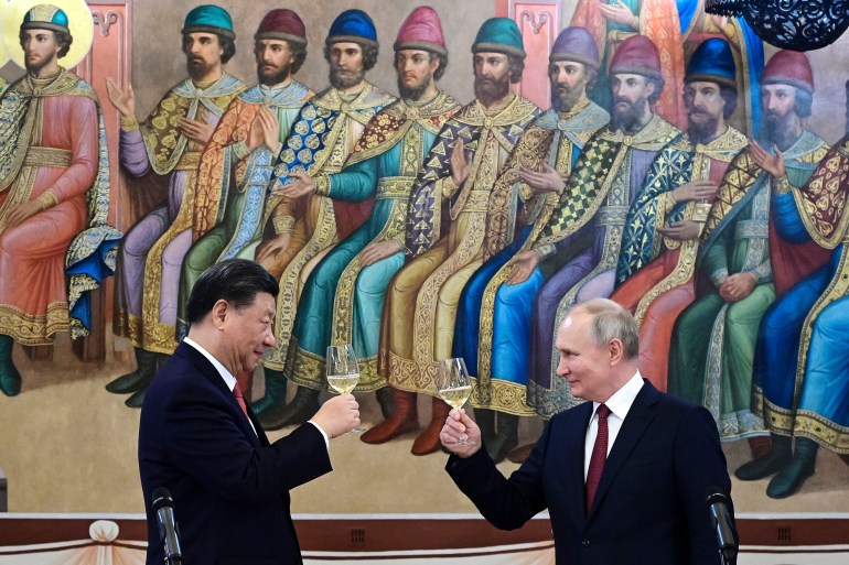 Xi Jinping and Vladimir Putin make a toast. They are in The Palace of the Facets in the Kremlin. There is a mural dating from Tsarist time behind them.