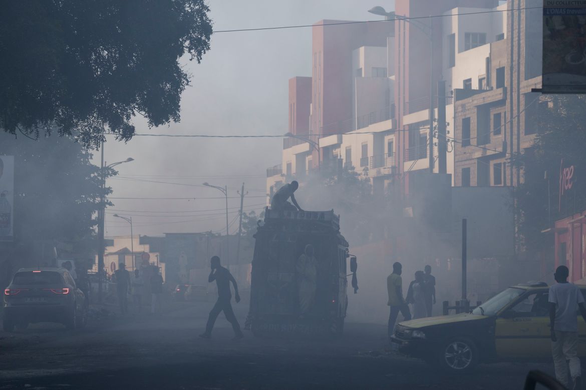 People cross a street through the smoke during clashes
