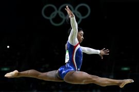 A woman gymnast does a split flying through mid-air.