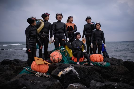 In a photo taken on November 6, 2015 a group of 'Haenyeo' pose for photographers as they perform a demonstration during a media event organised by the Foreign Press Center, on South Korea's southern island of Jeju