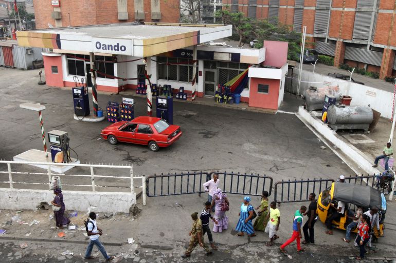 People walk past a closed fuel station in Lagos January 2, 2012