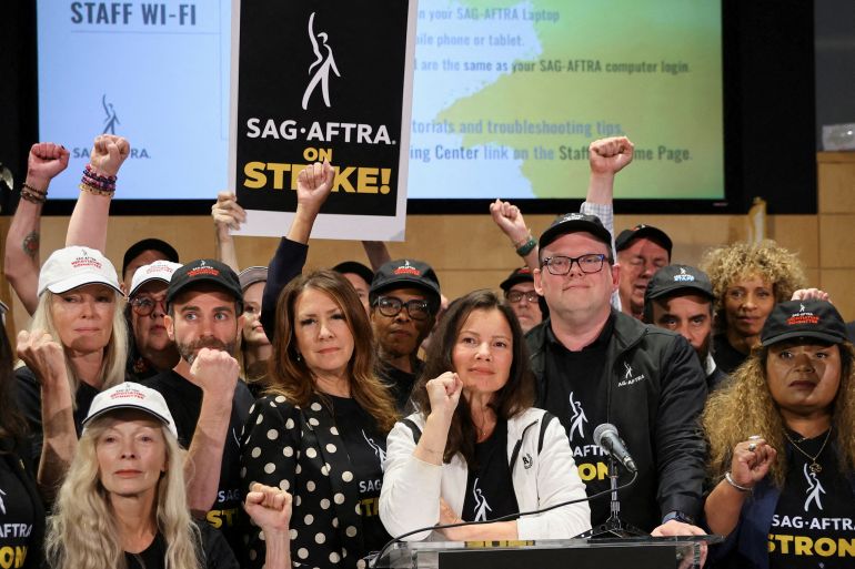 SAG-AFTRA union President Fran Drescher and other leaders of the SAG-AFTRA union after talks with studios ended in failure. She has her fist raised and the others are punching the air. One has a placard reading 'SAG-AFTRA on STRIKE'