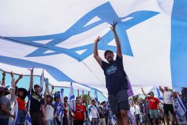Protesters hold up a large Israeli flag at a demonstration following a parliament vote on a contested bill that limits Supreme Court powers to void some government decisions, in Jerusalem July 24, 2023