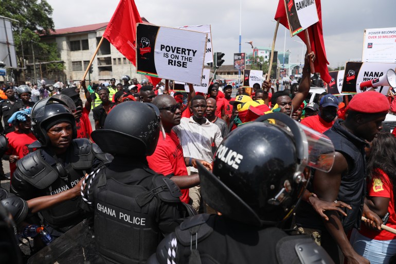 Police officers stand guard as protesters march during a demonstration on the current Cedi currency depreciation in the history of the country, a hike in fuel prices, and the general economic hardship, and asking Ghana President Nana Akufo-Addo and his deputy Mahamudu Bawumia to resign, in Accra, Ghana, on November 5, 2022. (Photo by Nipah Dennis / AFP)