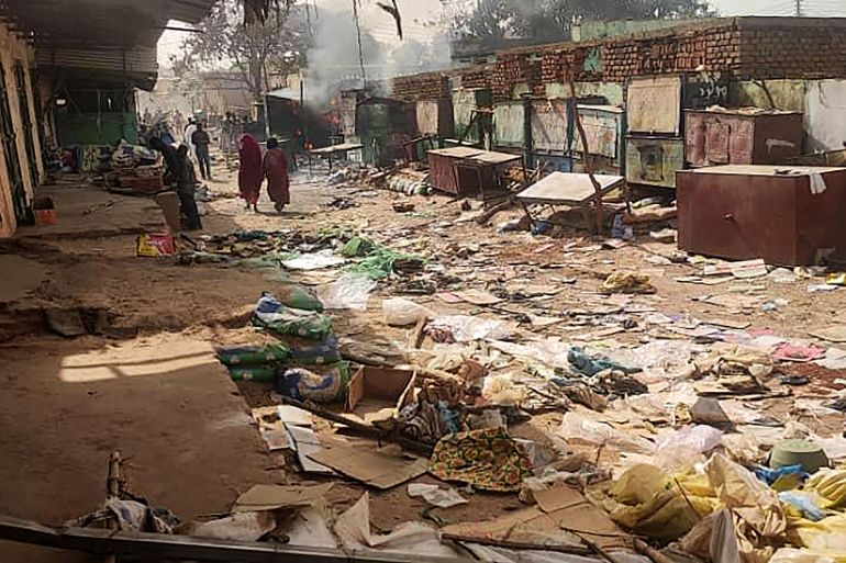 People walk among scattered objects in the market of El Geneina, the capital of West Darfur, on April 29, 2023, as fighting continues in Sudan between the forces of two rival generals