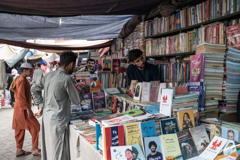 Afghan people scroll through books at a bookshop along a road in Kabul on June 27, 2023. (Photo by Wakil KOHSAR / AFP)