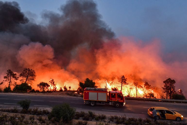 A fire truck moves along a road as a forest fire rages near the town of Melloula in northwestern Tunisia