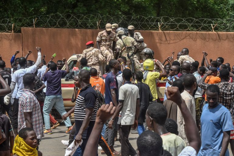 Protesters cheer Nigerien troops as they gather in front of the French Embassy.