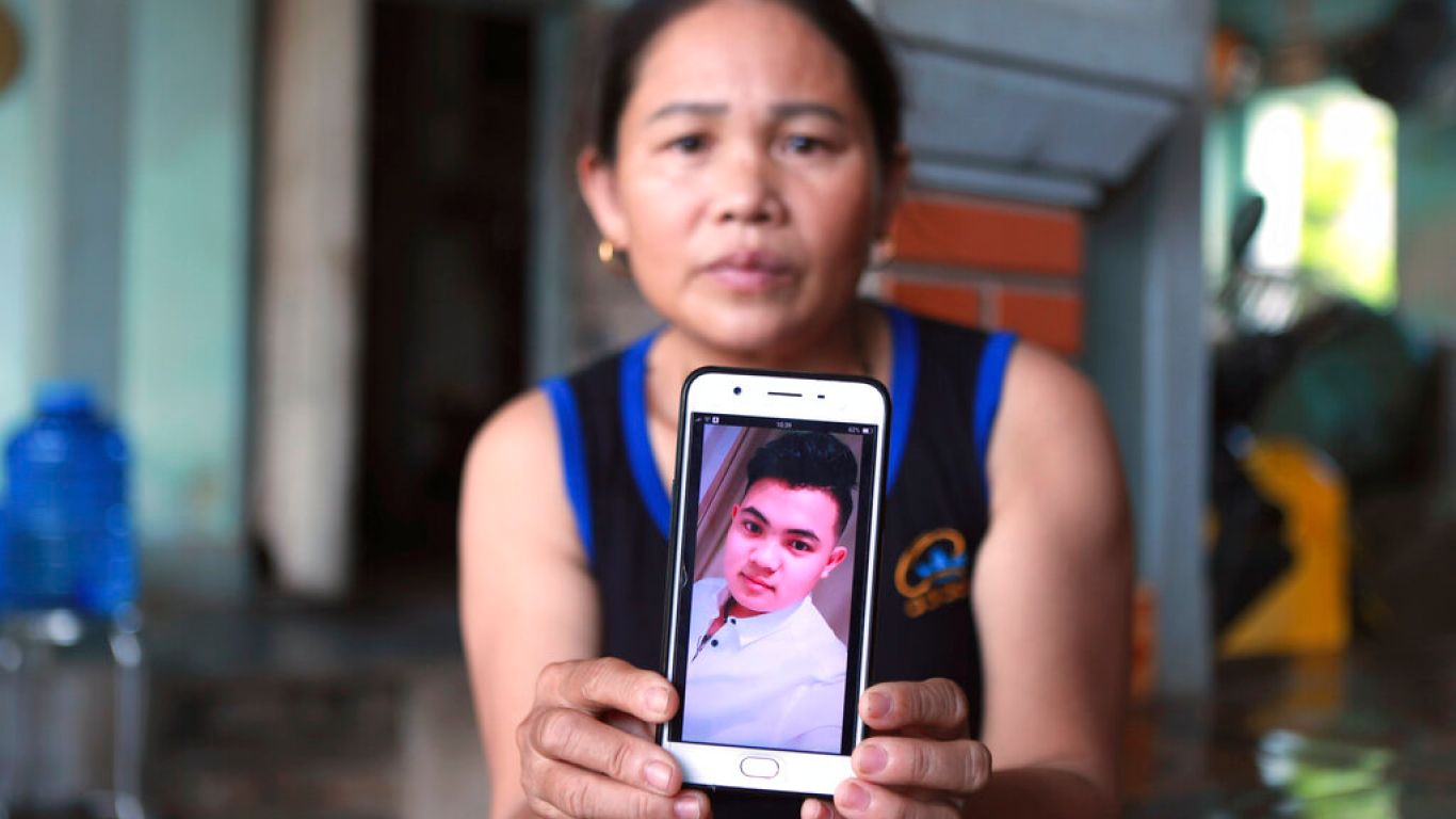 Hoang Thi Ai holds up her phone showing a photo of her son Hoang Van Tiep, who she fears is one of the possible victims in the truck deaths in England, at her home in Dien Chau district, Nghe An province, Vietnam on Monday, Oct. 28, 2019. Families in central Vietnam continue to cling on hope for the fates of their loved ones, who might be among the dead in a truck in southern England. (AP Photo/Hau Dinh)