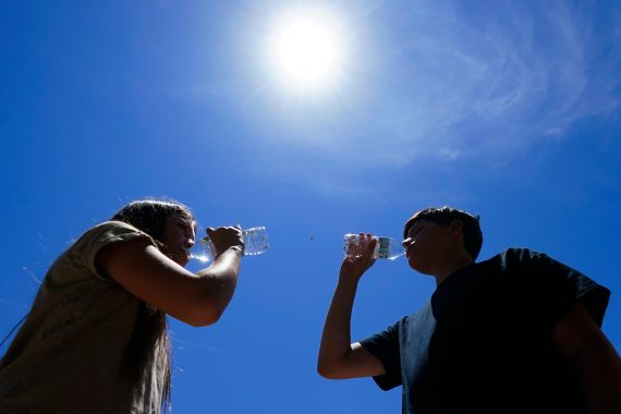 People drink from water bottles under a blazing sun in Phoenix, Arizona