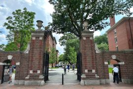 Students walk through a stately brick gate at Harvard University.