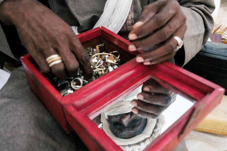 Almounzer Dicko sets up a display table taking jewelry out of boxes and bags he carries around in Cap Skirring in Casamance carrying his jewelry in bags and boxes from Mali approaching tourists on the beach to buy his products