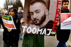 A woman holds a poster of rapper Toomaj Salehi, who was handed a prison sentence over his support of the Mahsa Amini protests [File: Robert Deyrail/Gamma-Rapho via Getty Images]