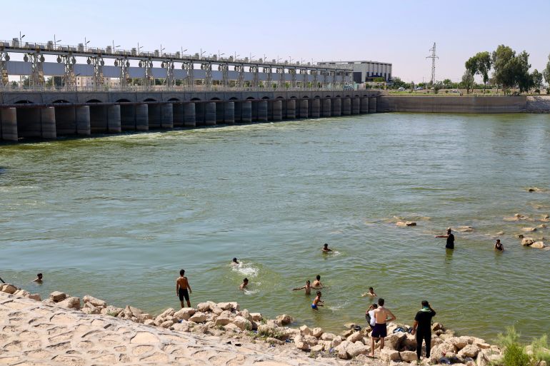 Men splashing in the Euphrates River in June, [Alannah Travers/Al Jazeera]