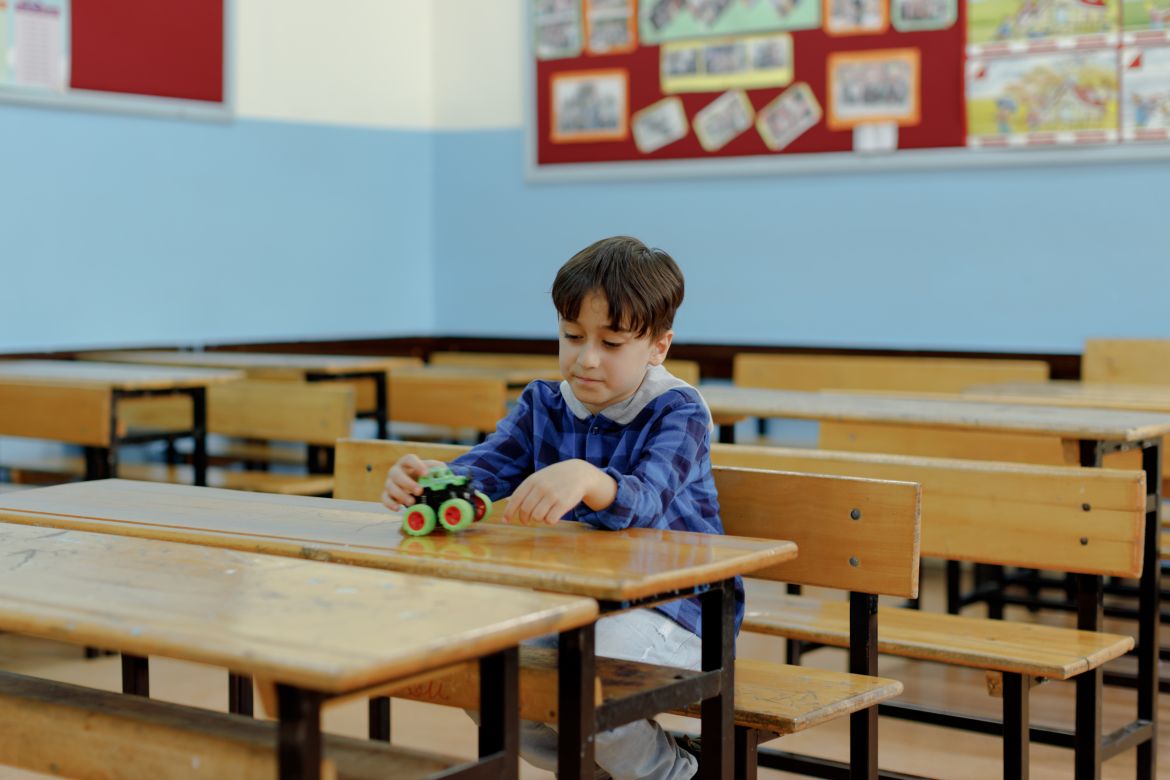 Eymen, 8, plays with his shining green toy car