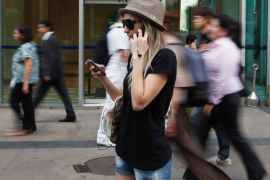 A woman uses mobile phones as she talks, writes a message and listens to music in Sao Paulo, Brazil