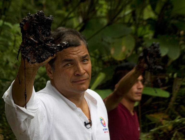 Former Ecuadorian President Rafael Correa lifts an oil-covered hand as he tours Aguarico's forests in 2013.