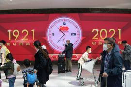 Travellers walk past a giant screen clock marking the 100th founding anniviersary of the Communist Party of China, at the Beijing Daxing International Airport on the first day of Labour Day holiday, in Beijing, China May 1, 2021. REUTERS/Tingshu Wang