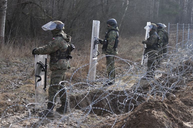 Members of the Polish Border Guard and Polish soldiers, stand guard at the construction site of a barrier at the border between Poland and Belarus in Tolcze near Kuznica, Poland.